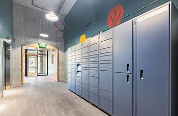 A hallway with a row of lockers on the right and a doorway on the left.